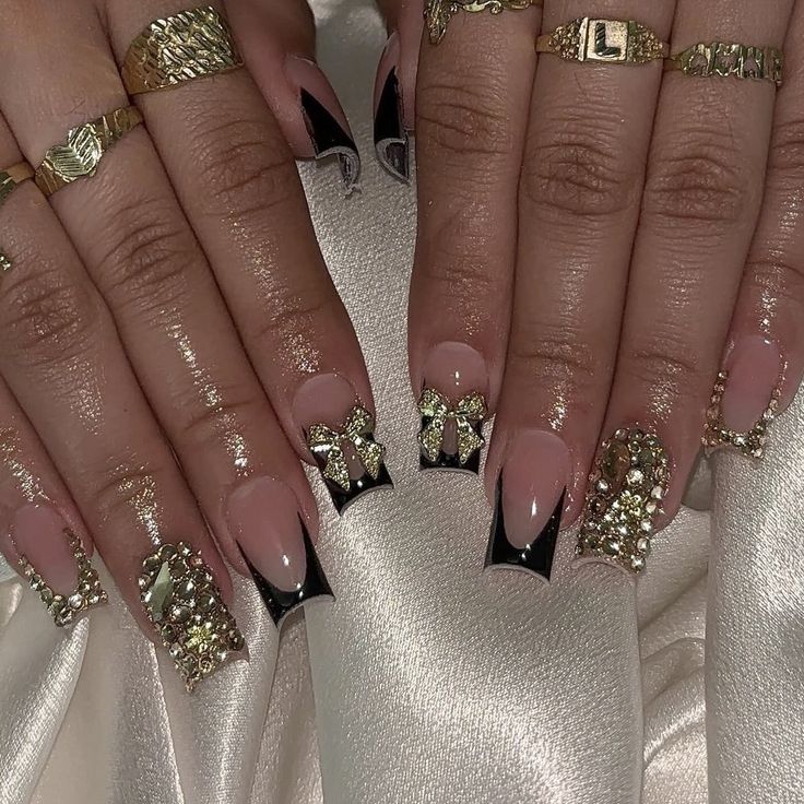 Luxurious Nude and Black Nail Design with Glamorous Gold Accents and Gems.