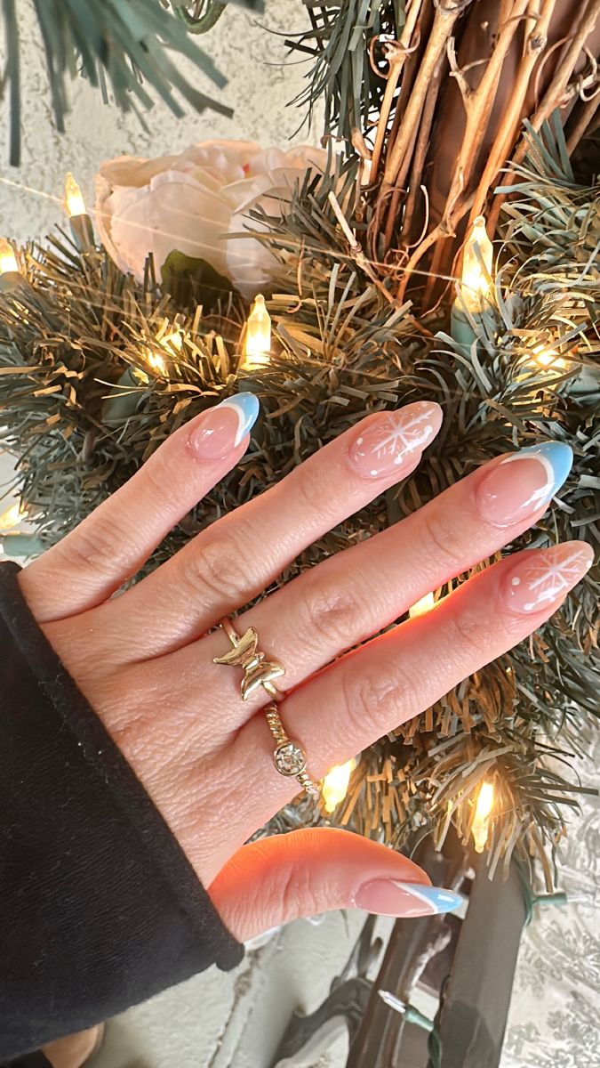 Elegant Winter Nail Design: Soft Nude Base with Blue Tips and Snowflake Accents.