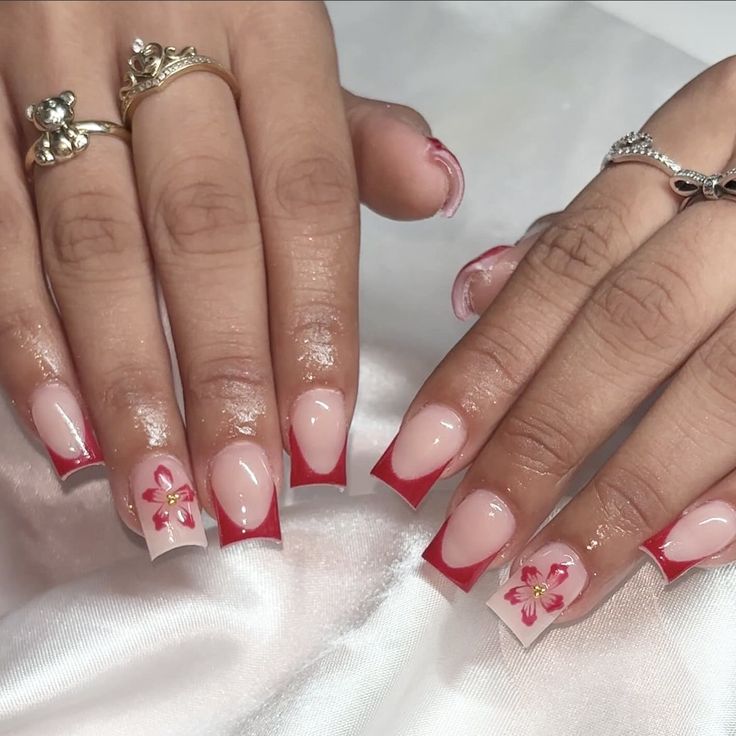 Chic French Tip Nail Design with Pink Floral Accents and Bold Red Highlights.