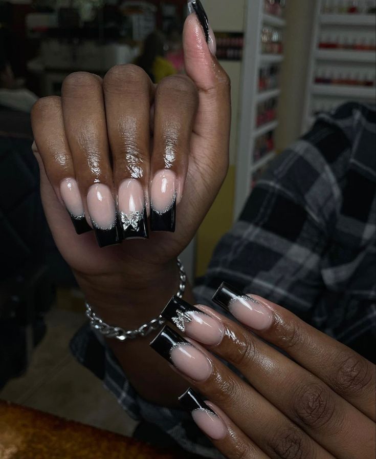 Sophisticated French Tip Nail Design with Nude, Glossy Black, and Silver Accents.