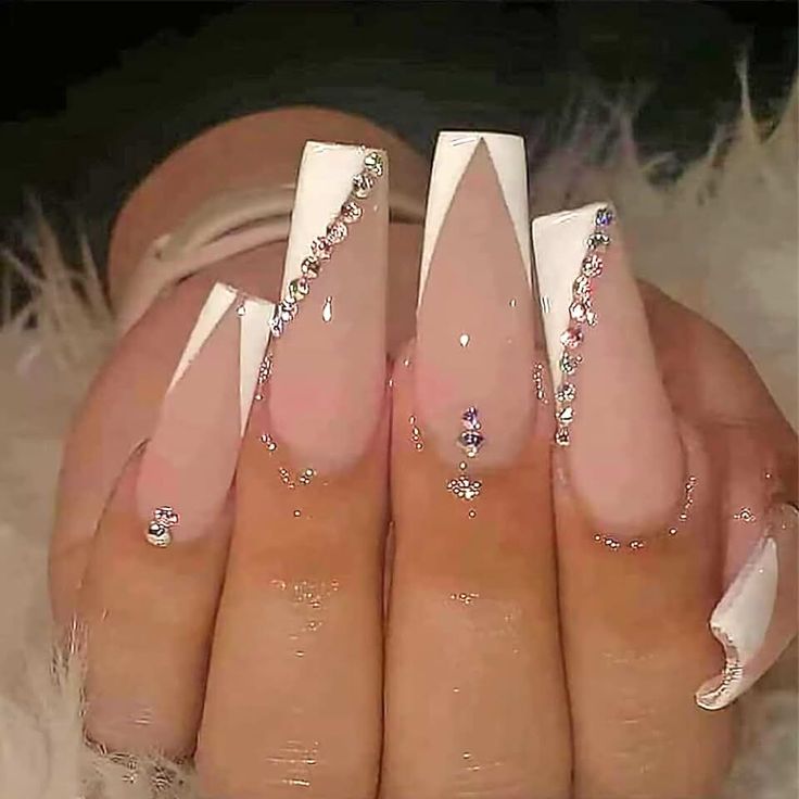 Chic Stiletto Nail Design with Nude and White Tips, Accented by Rhinestones and Geometric Patterns.