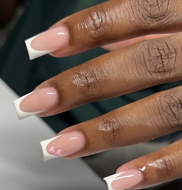 Chic Almond-Shaped French Manicure with Nude Base, White Tips, and Whimsical Pink Heart Accent.