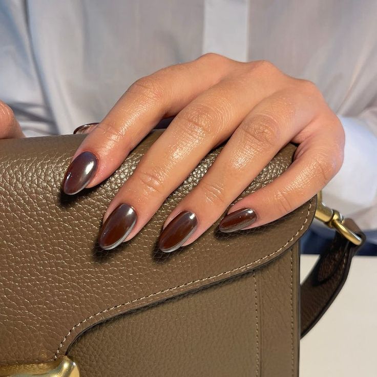 Sophisticated Chocolate Brown Gradient Almond Nails Complement Chic Handbag.