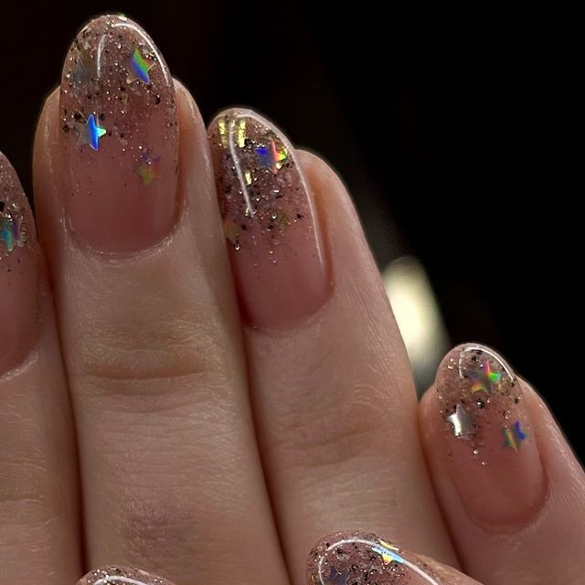 Chic Sparkling Nude Nails with Holographic Glitter and Whimsical Star Flakes.