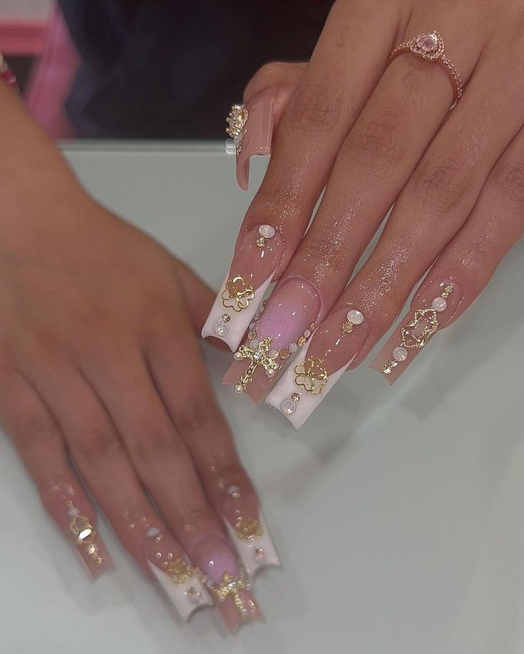 Sophisticated Nail Design with Elongated Square Tips, Soft Pink and Glossy White Polish, Gold Accents, and Sparkling Rhinestones.