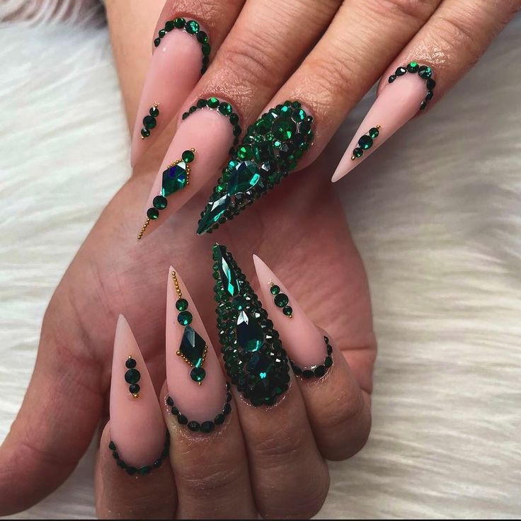 Striking Stiletto Nails: Matte Nude with Glimmering Green Rhinestones for Sophistication and Glamour.