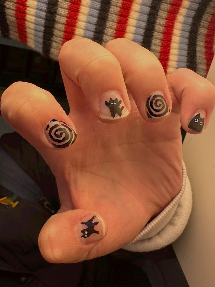 Playful Whimsical Nail Art: Black Cat and Spiral Motifs on a Nude Base.