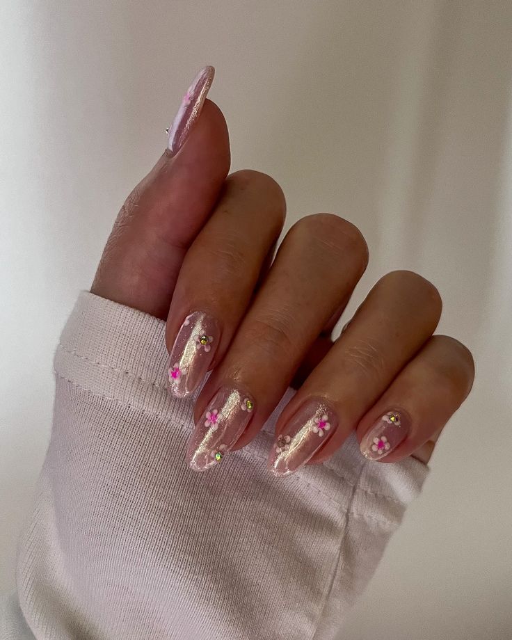 Charming Soft Pink Nail Design with Shimmering Accents and Floral Patterns.