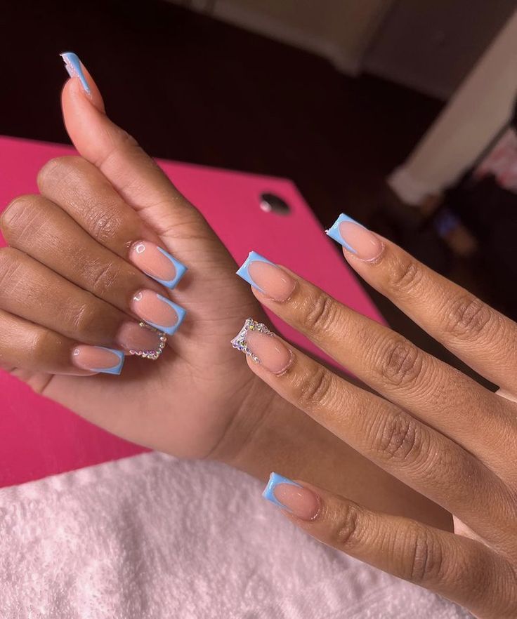 Chic Soft Nude Nails with Baby Blue Tips and Sparkling Gem Accent.