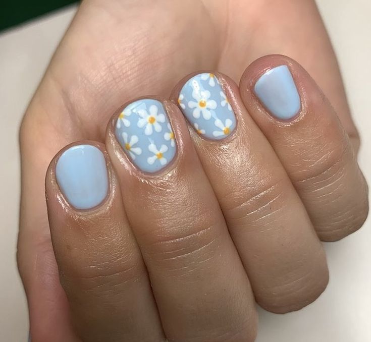 Charming Floral Nail Design: Soft Blue Base with Daisies and Yellow Accents.