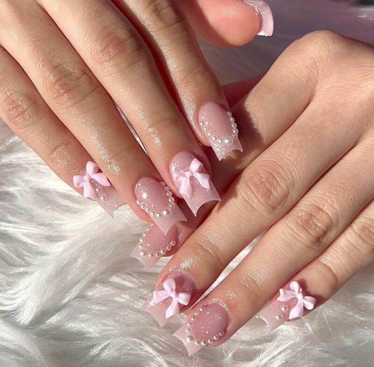 Elegant Pink Nail Design with Intricate Bows and Pearl Accents.