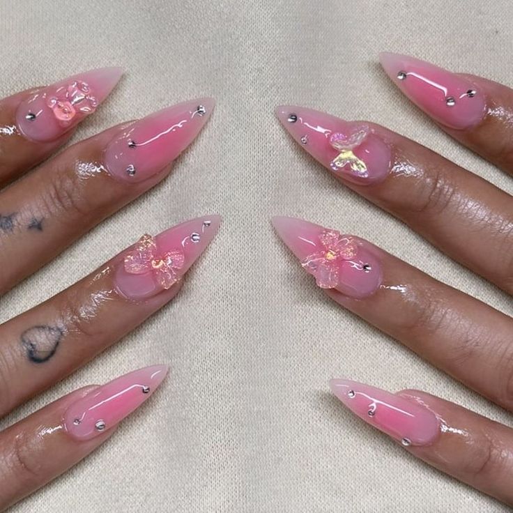 Whimsical Pink Stiletto Nails with Floral Embellishments for a Chic Aesthetic.