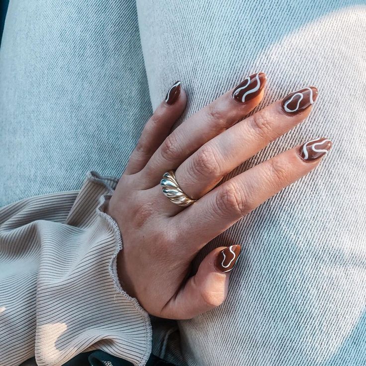 Elegant Almond-Shaped Nails with Chocolate Brown Base and Delicate White Swirls.