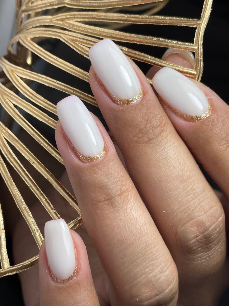 Sophisticated Soft White Nail Design with Delicate Gold Glitter French Tips