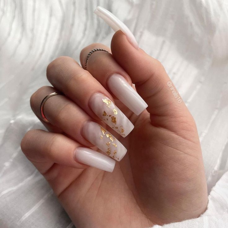 Chic Manicure: Glossy White and Soft Pink Nails with Gold Leaf Accents.