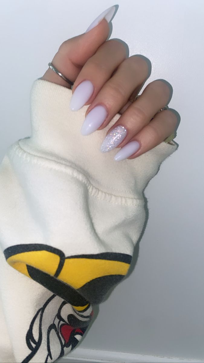 Chic Almond-Shaped Lavender Nails with Glitter Accent Complement a Cozy Sweater.