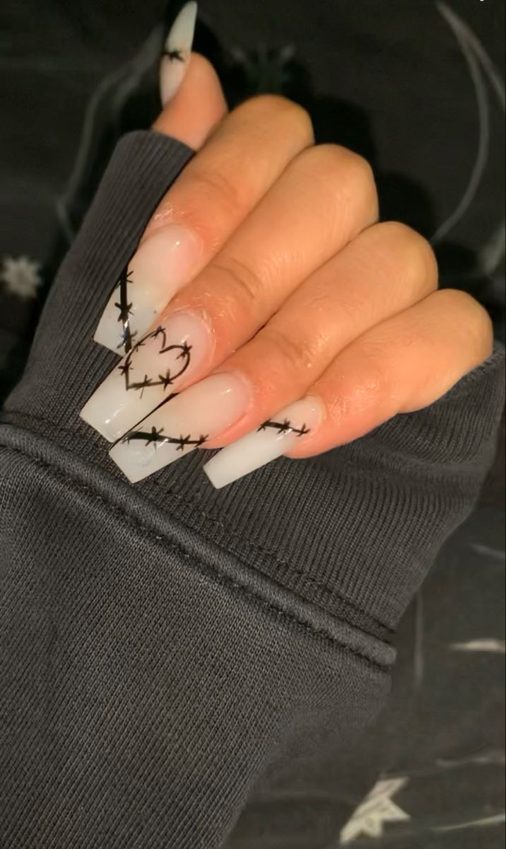 Chic Nail Design: Elongated Translucent Tips with Edgy Black Barbed Wire Patterns.