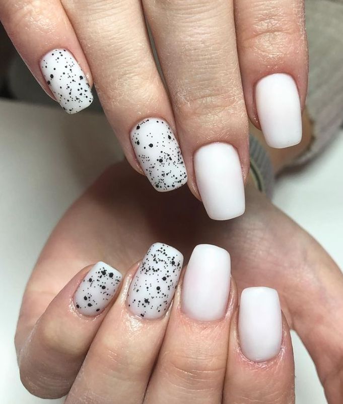 Chic Minimalist Nail Design: Matte White and Speckled Black Elegance.