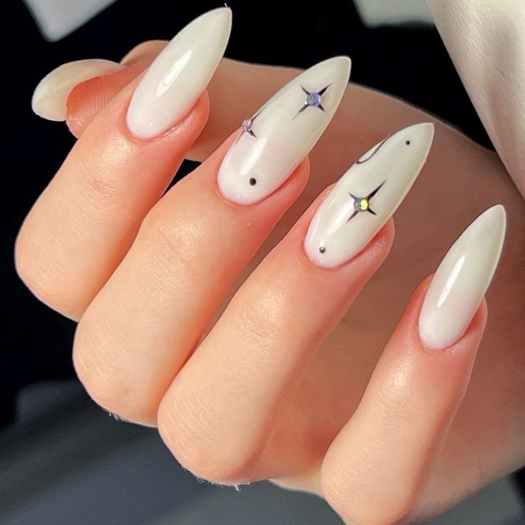 Sophisticated Almond-Shaped Nails with Glossy White Finish and Star Gemstone Accents.