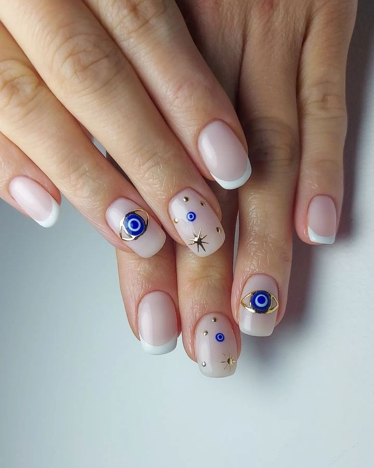 Chic Nude French Tip Nails Adorned with Gold and Blue Embellishments for Versatile Elegance.