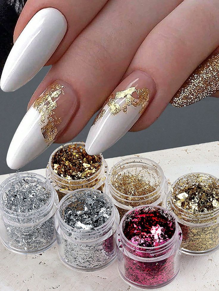 Chic Elegant Nail Design: Elongated White Nails with Gold Foil Accents and Playful Glitter Touches.