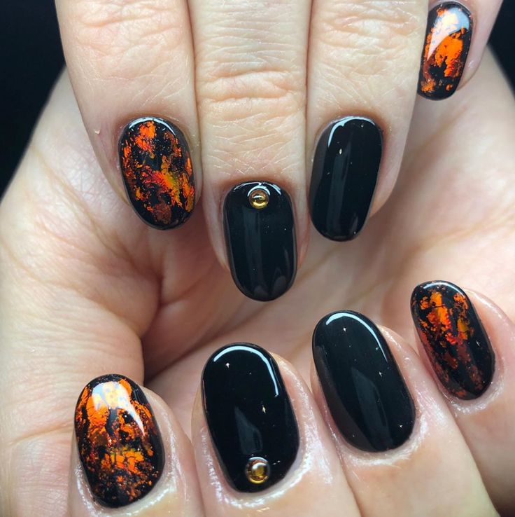 Bold Black Nails with Vibrant Orange and Yellow Accents: A Striking Blend of Elegance and Edginess.