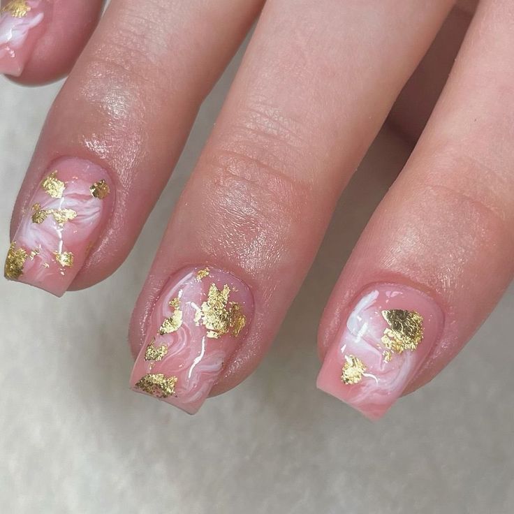 Sophisticated Elegant Nail Design: Soft Pink Base with Swirling White and Gold Accents, Enhanced by Luxurious Gold Flakes.