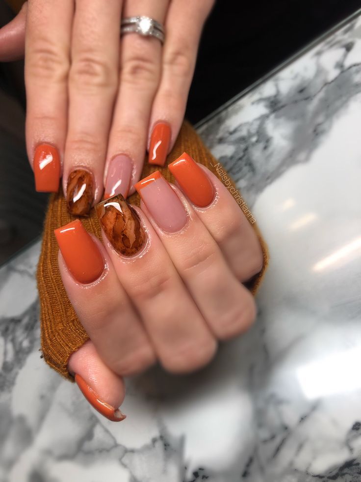 Chic Autumn-Inspired Nail Design with Bold Orange and Marbled Accents.