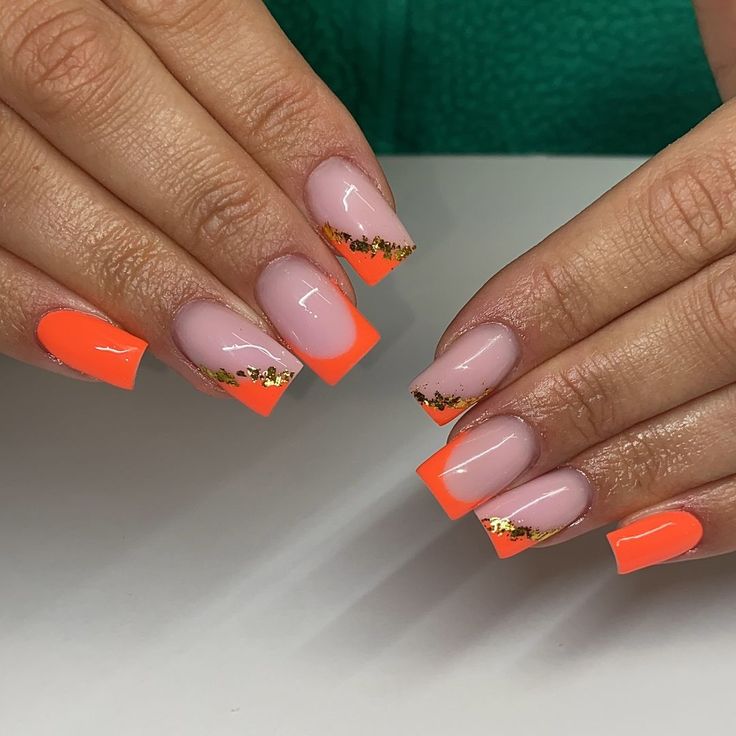 Vibrant Neon Orange and Nude Nail Design with Gold Leaf Accents for a Luxurious Statement Look.