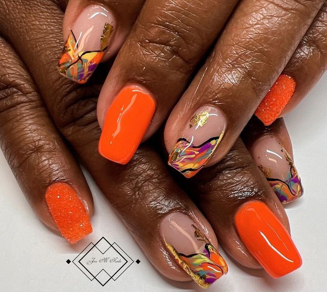 Bold and Elegant Orange Nail Design with Artistic Patterns and Golden Highlights.