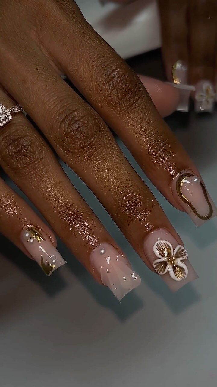 Sophisticated Nude Nail Design with Gold Accents and Floral Motif.