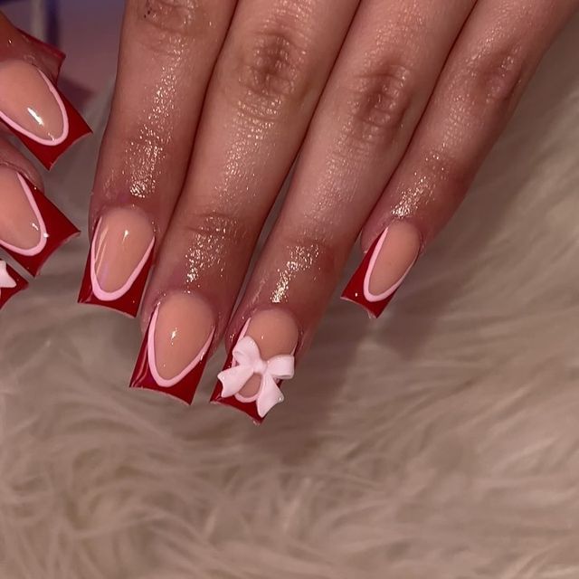 Chic Bold Red and Nude Nail Design with Elegant White Accents and Playful Bow.