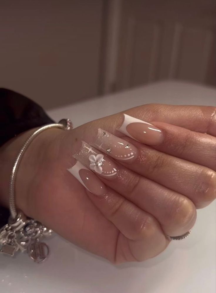 Sophisticated Elegant Nail Design: Nude and White with Bow Accents and Sparkling Embellishments.