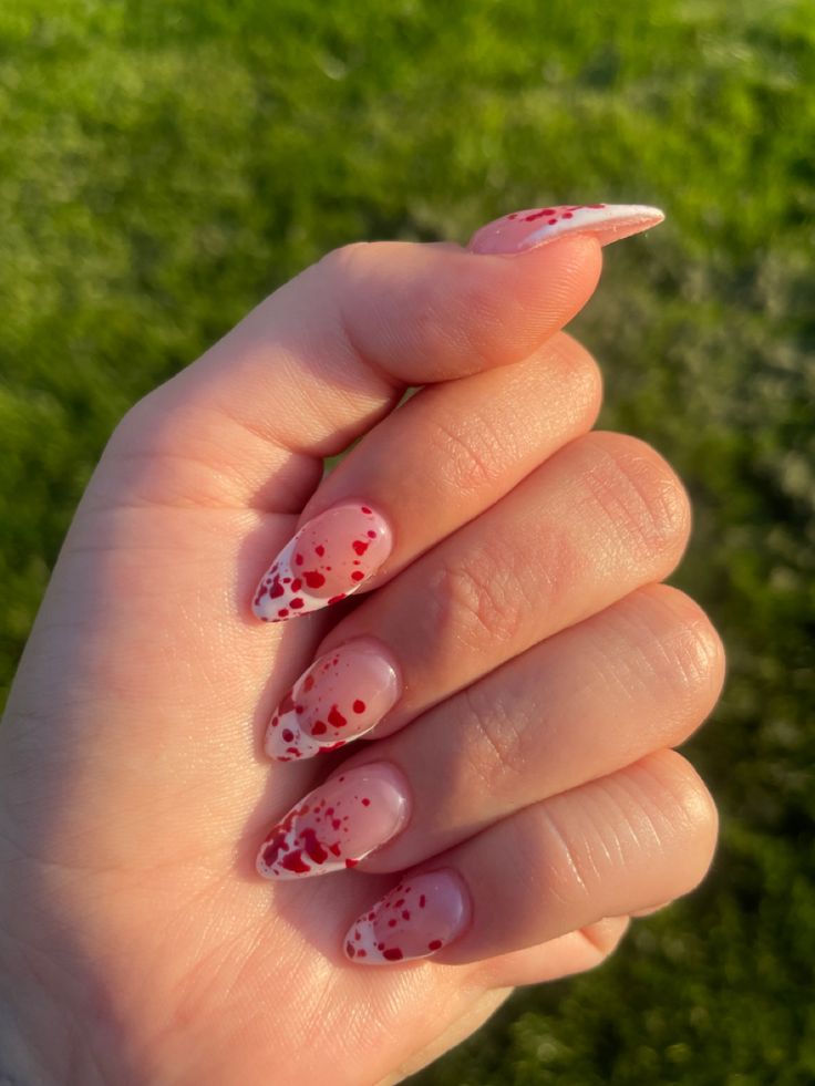 Elegant Nail Design: Playful Soft Pink and Striking Red Splatter for a Statement Look.