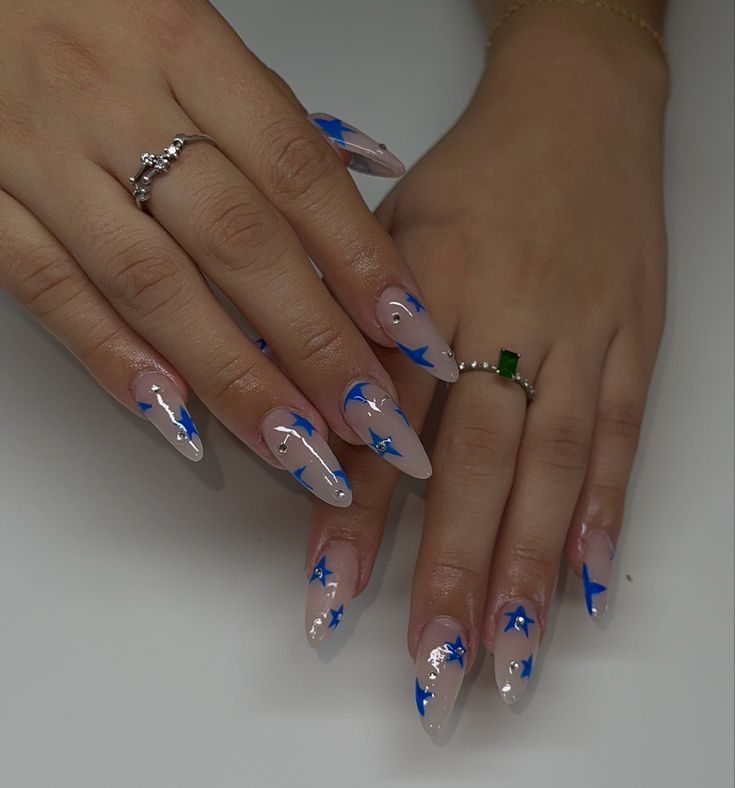 Sophisticated Almond-Shaped Nail Design: Soft Nude with Vibrant Blue Stars and Delicate Accents.