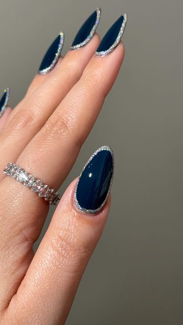 Sophisticated Dark Blue Almond-Shaped Nails Enhanced with Shimmering Silver Edges and a Delicate Silver Ring.