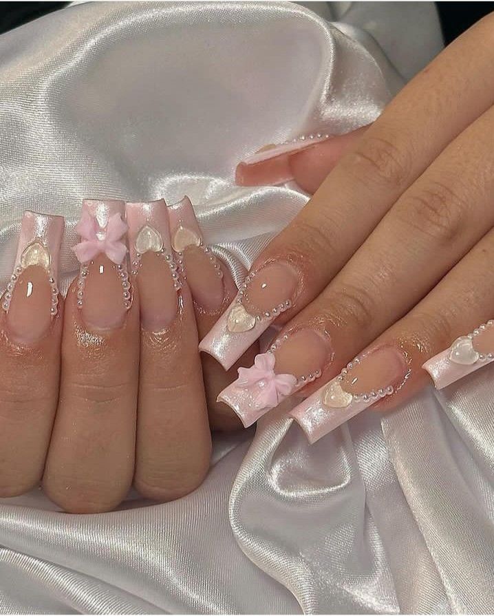 Charming Pastel Pink Nail Design: Glossy Ribbons, Pearl Accents, and Floral Appliques for Special Occasions.