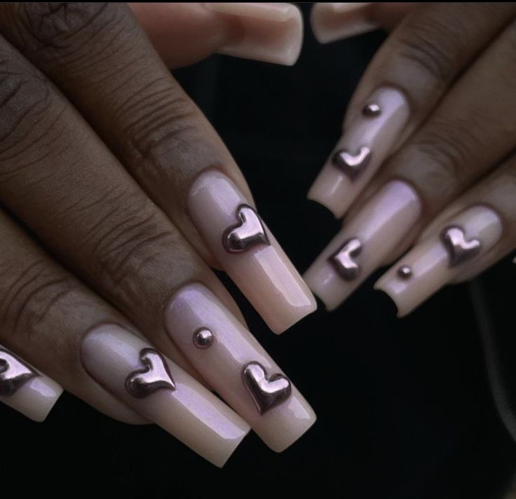 Chic Heart-Inspired Nail Design: Soft Nude Base with Metallic Accents.