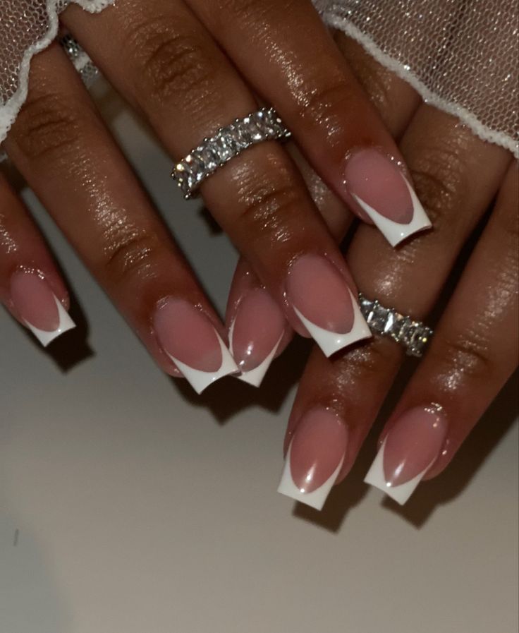 Elegant French Manicure with Soft Pink Base and Crisp White Tips, Enhanced by Sparkling Rings for Sophisticated Occasions.