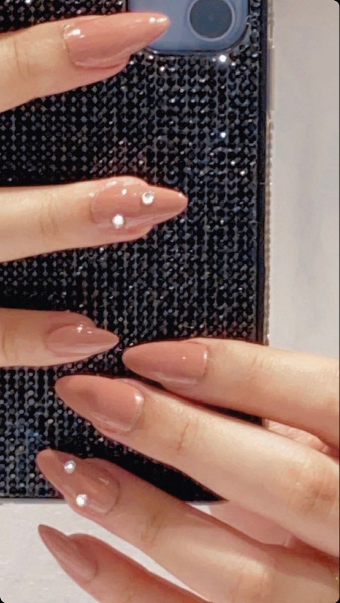 Chic Almond-Shaped Nude Nail Design with Rhinestones and Glossy Finish.