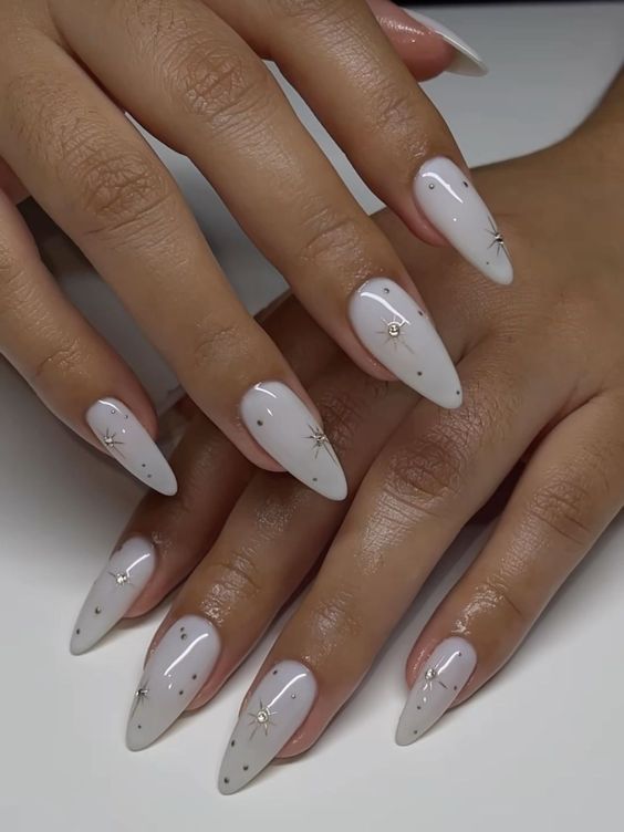 Chic Almond-Shaped Nails with White Polish and Gold Star Accents for a Minimalist Glamour.