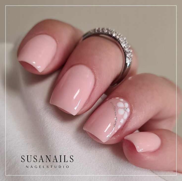 Elegant Glossy Pink Nails with Floral Design and Sparkly Ring Accents.