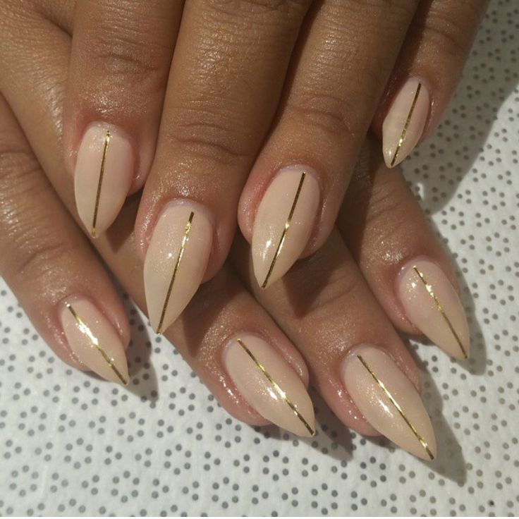 Chic Almond-Shaped Nails: Soft Nude Base with Glamorous Gold Striping.