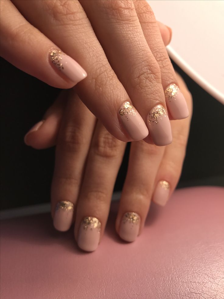 Sophisticated Nude Nail Design with Subtle Shimmer and Gold Glitter Accents.