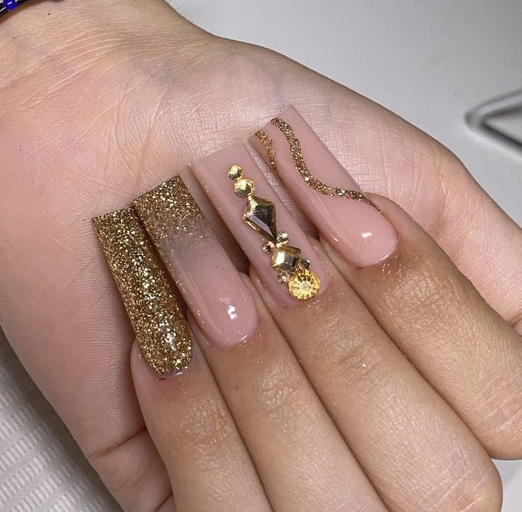 Luxurious Nude and Gold Almond-Shaped Nail Design with Intricate Embellishments