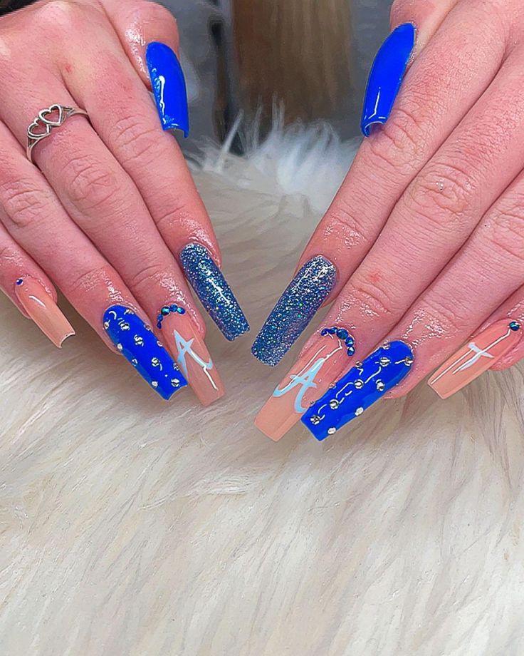 Vibrant Nail Art: Bold Blue and Soft Nude Design with Glitter Accents and Unique Embellishments.