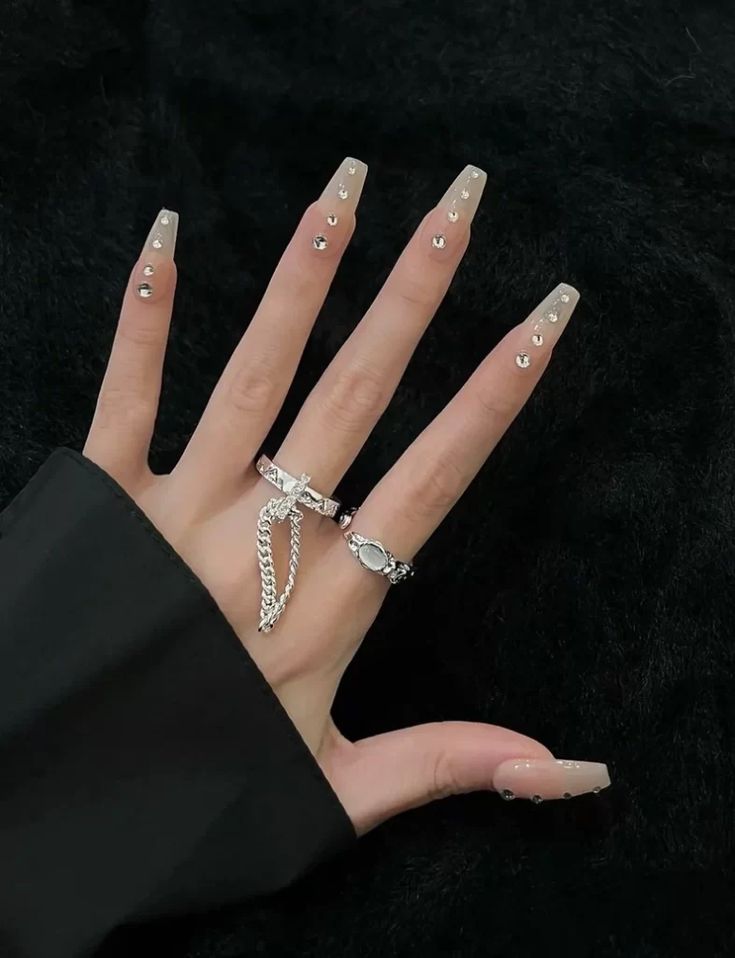 Chic Long Nude Stiletto Nail Design with Silver Rhinestones and Jewelry.