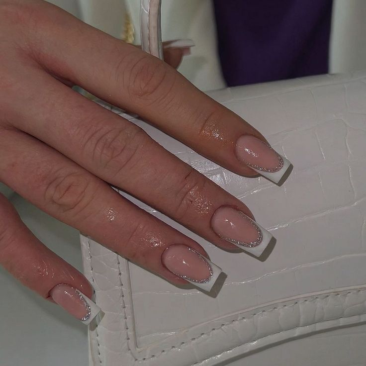 Chic Blush and White French Manicure Enhanced with Silver Accents and Paired with Stylish Handbag.