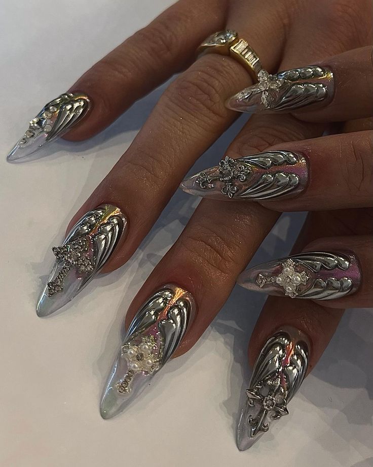 Elegant Elongated Metallic Silver Nail Design with Wing Patterns and Sparkling Embellishments.