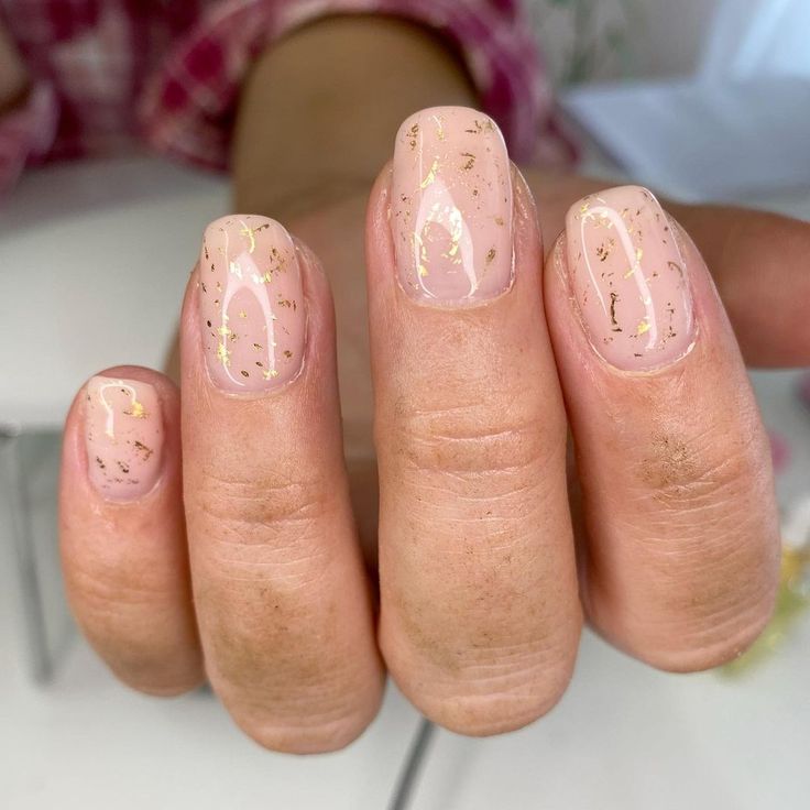 Sophisticated Nude Nail Design with Delicate Gold Flakes and Glossy Finish.